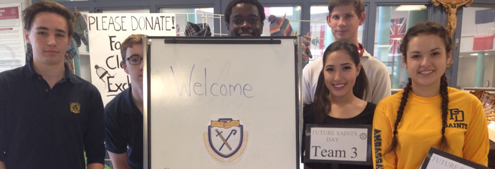 Students standing beside welcome sign